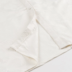 Detailaufnahme des weißen Kleides mit Blatt-Jacquard-Muster und Knopfdetails