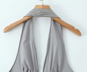 Detail eines hellgrauen Satinkleids mit Neckholder-Ausschnitt und schwarzen Punkten
