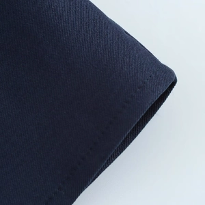 Détail du tissu bleu marine avec une couture précise à aiguille unique sur l'ourlet