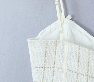 Détail du tissu en tweed blanc avec fils métalliques dorés et fines bretelles réglables