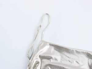 Detail of silver metallic foil pleated dress featuring adjustable thin shoulder straps