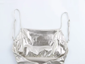 Close-up of metallic silver fabric with reflective foil texture and thin spaghetti straps