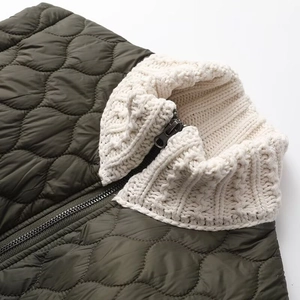 Detail of army green quilted nylon jacket with off-white ribbed knit stand collar