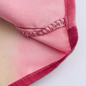 Dettaglio ravvicinato del tessuto in raso sfumato rosa con cuciture rosse rinforzate