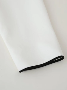 Dettaglio della manica di un abito bianco con piping nero e trama di tessuto fine
