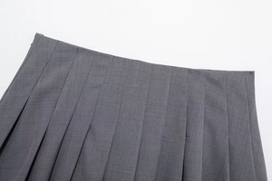 Dettaglio della gonna a pieghe grigio scuro con cuciture in vita e cerniera invisibile