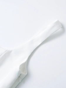 Détail du haut court blanc avec de larges bretelles et une fermeture éclair invisible