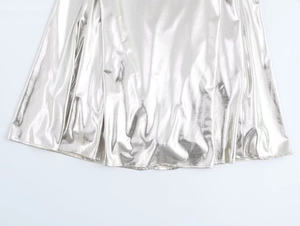 Detail of silver metallic foil fabric with reflective pleated texture and liquid finish