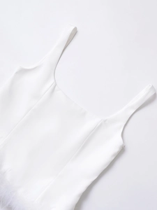 Détail du débardeur blanc avec bordure en plumes luxueuses et tissu brillant