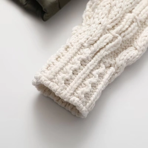 Close-up of white cable knit cuff and dark green quilted fabric on a nylon jacket