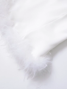 Gros plan détaillé montrant les plumes blanches douces et la texture du tissu du crop top