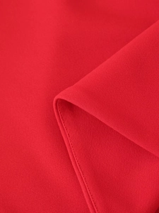 Primer plano detallado de tela roja texturizada con costuras finas y caída suave natural