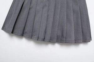 Dettaglio della gonna a pieghe grigia con pieghe nette e tessuto in twill strutturato