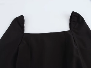 Vue détaillée de l'encolure carrée et des smocks élastiques sur cette robe noire élégante