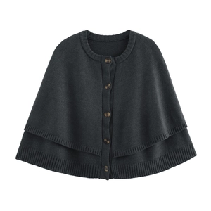 Detail of dark grey knit poncho featuring amber buttons and layered ribbed hem texture