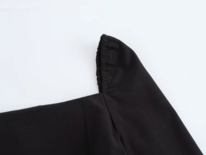 Détail de l'encolure carrée et de l'épaule plissée élastique sur une robe courte noire