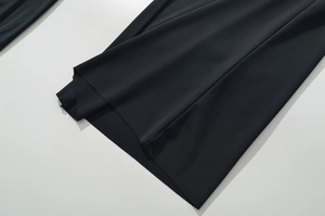 Detailed view of the high-stretch black fabric hem with professional stitching on women's pants