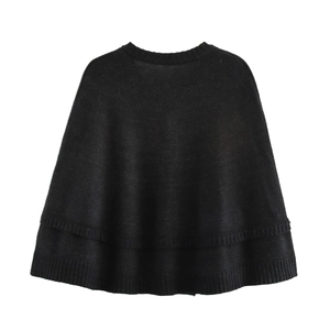 Detail view of the black knit poncho showing the double-layered hem and ribbed edge design