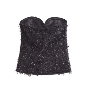 Detail van zwarte strapless top met glinsterende pailletten en gevederde franje accenten