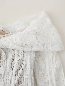 Détail de la robe en dentelle blanche avec broderies florales et plis verticaux