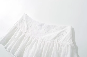 Detail of white Broderie Anglaise lace fabric and ruffled waist design on short skirt