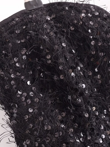 Detailopname van zwarte paillettenborduursels en veren franjes op een strapless korsettop