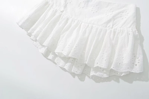 Detailed view of layered eyelet lace ruffles on a white bohemian mini skirt