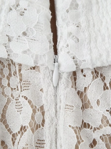 Gros plan sur la dentelle florale blanche avec détail de la fermeture éclair invisible