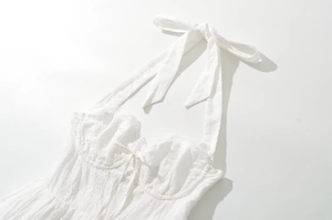 Detail of white lace halter dress showing delicate embroidery and structured sweetheart neckline