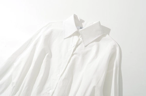 Detailed view of a white long-sleeve button-up shirt with classic collar and cotton texture