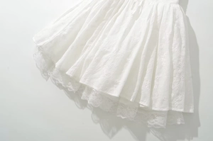 Close-up detail of white floral embroidery and delicate lace trim on the dress hemline