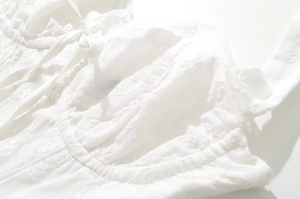 Close-up of white floral embroidery and lace details on a chic halter dress