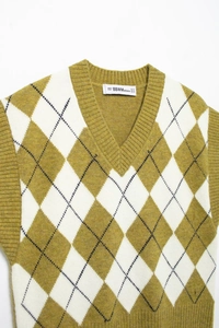 Detail of V-neck sleeveless knitted vest with olive green and white argyle pattern texture