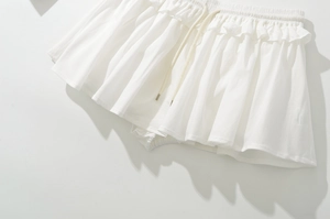 Detail of white drawstring elastic waistband with metallic caps and ruffled skirt layers