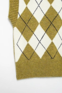 Detail showing green and white argyle knit pattern and ribbed hem of the stylish vest