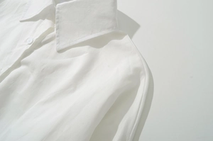 Close-up of a white long-sleeve cotton shirt featuring a classic collar and button detail
