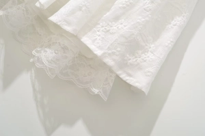 Detail of white embroidery flower fabric and delicate eyelash lace hem on a dress