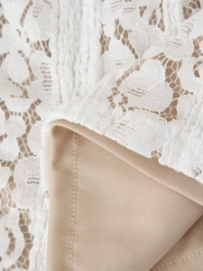 Gros plan sur tissu en dentelle florale blanche avec doublure nude et coutures précises