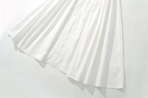 Primo piano dei dettagli in cotone plissettato bianco e dell'orlo del vestito