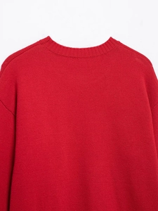 Close-up of red knit sweater featuring a ribbed crew neck and high-quality texture