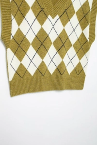 Close-up of diamond argyle knit pattern and ribbed V-neck on men's sweater vest