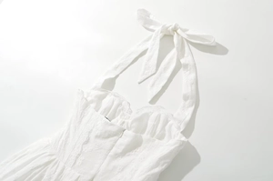 Close-up of white halter dress featuring intricate floral lace and ruffled neckline