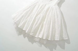 Detailed view of white floral embroidery and delicate lace hem on a chic spring dress