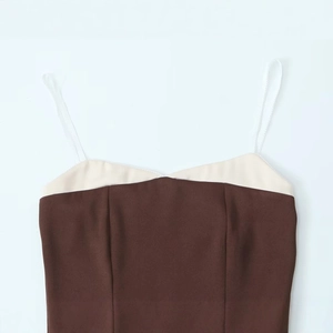 Detailed view of the contrast beige neckline and white lace straps on a brown top