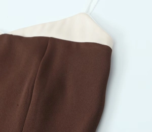 Detail view of the contrast color stitching and thin straps on the dark brown top