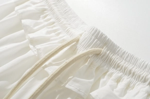 Detail of white cotton A-line skirt featuring elastic ruffled waistband and woven drawstring