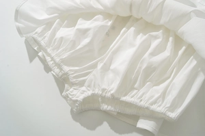 Detailed close-up of elastic gathered waistband on a white cotton shirt and skirt set