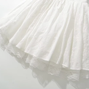 Elegant white halter dress with intricate floral embroidery and delicate lace patchwork hem