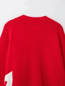 Macro detail of red knitted cardigan with soft textured fabric and white woven pattern