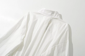 Detail view of white shirt lapel collar and pleated back stitching on cotton fabric
